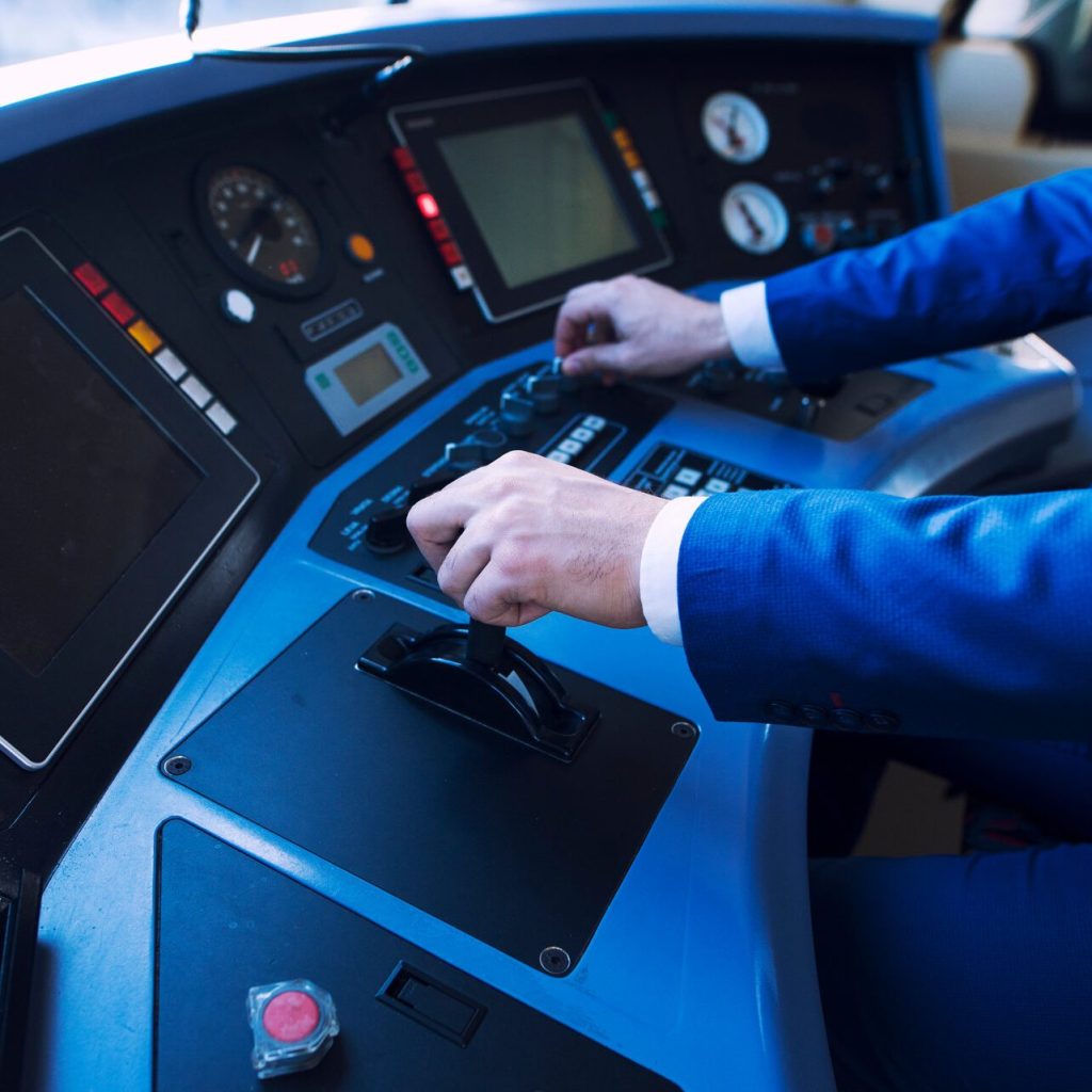 Mann bedient Hebel in Zugcockpit, Vs-rail24